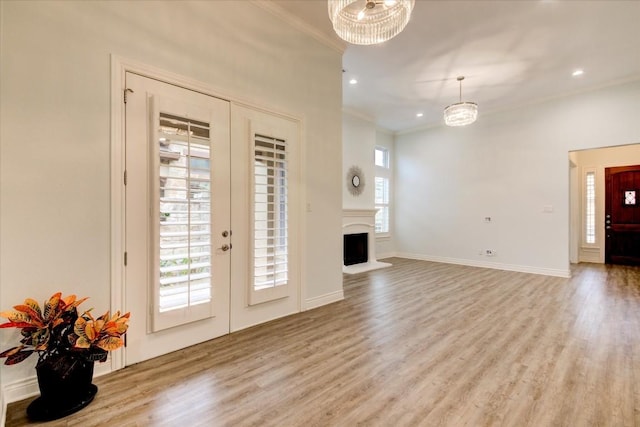 unfurnished living room with crown molding, a chandelier, and light wood-type flooring