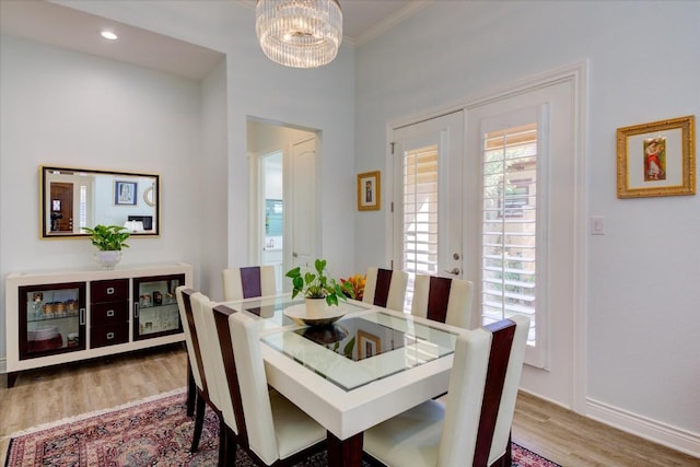 dining space featuring hardwood / wood-style floors, french doors, ornamental molding, and a notable chandelier