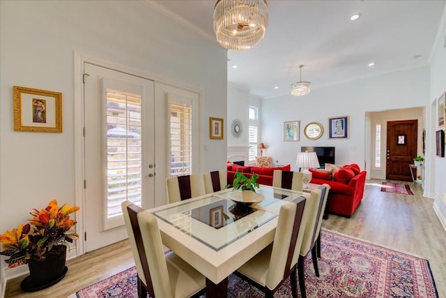 dining room featuring crown molding, french doors, light hardwood / wood-style flooring, and a chandelier