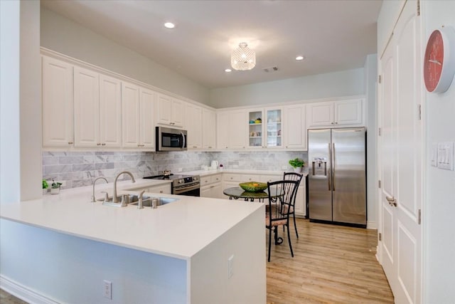 kitchen featuring kitchen peninsula, white cabinetry, sink, and appliances with stainless steel finishes