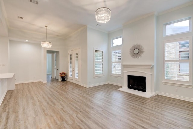 unfurnished living room with a high ceiling, light wood-type flooring, an inviting chandelier, and ornamental molding