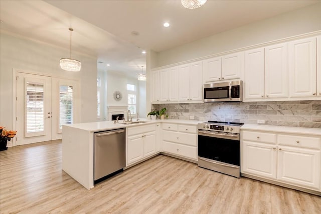 kitchen with white cabinets, kitchen peninsula, stainless steel appliances, and hanging light fixtures