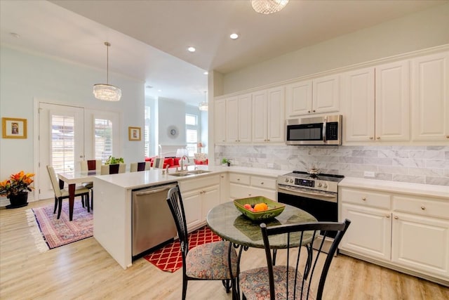 kitchen featuring decorative backsplash, stainless steel appliances, sink, pendant lighting, and white cabinets