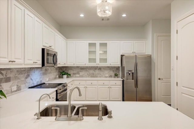 kitchen with hanging light fixtures, sink, appliances with stainless steel finishes, tasteful backsplash, and white cabinetry