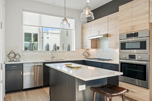 kitchen featuring pendant lighting, sink, a kitchen island, stainless steel appliances, and a kitchen bar