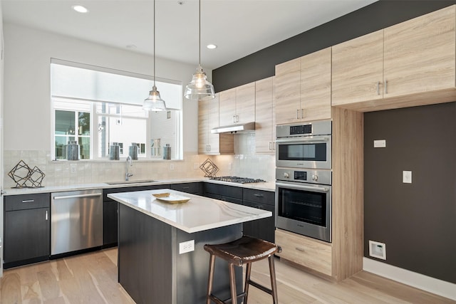 kitchen with a kitchen bar, sink, decorative light fixtures, a kitchen island, and stainless steel appliances