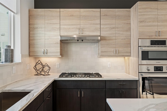 kitchen featuring light stone countertops, appliances with stainless steel finishes, sink, and backsplash