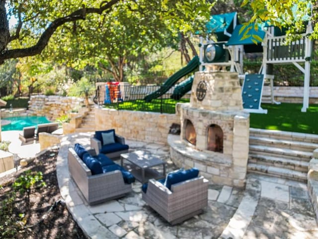 view of patio featuring an outdoor living space with a fireplace and a playground