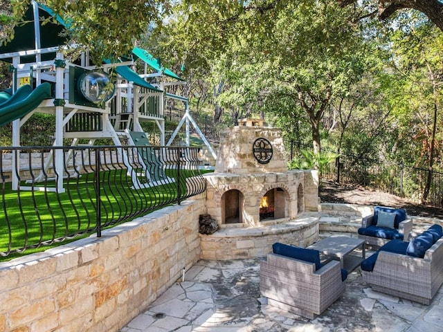 view of patio / terrace featuring an outdoor living space with a fireplace and a playground