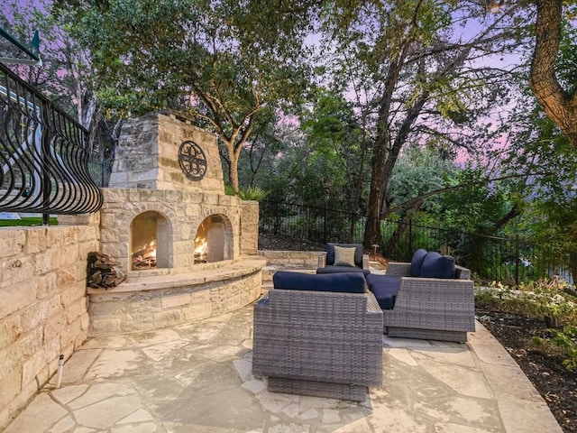 patio terrace at dusk featuring an outdoor living space with a fireplace