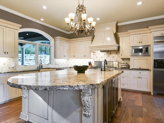 3001 Pescadero Cv, Austin, TX 78746 - kitchen with a kitchen island with sink, custom exhaust hood, built in appliances, and cream cabinetry