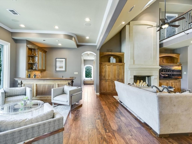 living room with a large fireplace, ceiling fan, dark hardwood / wood-style flooring, and crown molding