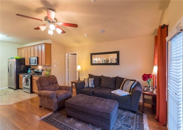 living room with ceiling fan, vaulted ceiling, and light hardwood / wood-style floors