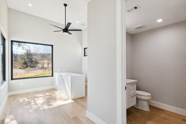 bathroom featuring a tub, ceiling fan, toilet, vanity, and hardwood / wood-style flooring