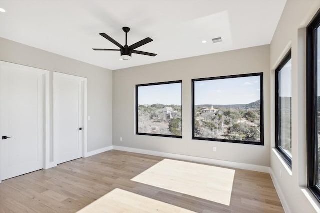 unfurnished bedroom featuring multiple closets, ceiling fan, and light wood-type flooring