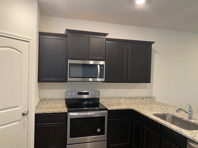 kitchen featuring light stone countertops, sink, and appliances with stainless steel finishes