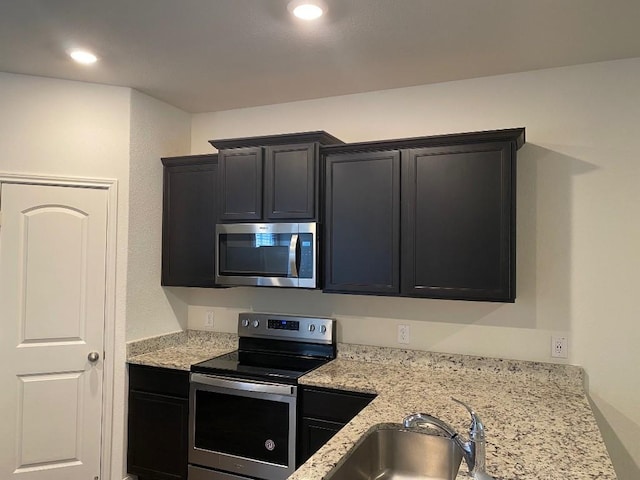 kitchen featuring light stone counters, sink, and appliances with stainless steel finishes