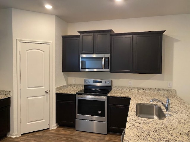 kitchen with light stone counters, dark hardwood / wood-style flooring, sink, and appliances with stainless steel finishes