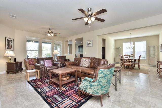 tiled living room with ceiling fan with notable chandelier