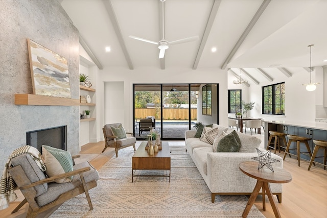 living room featuring lofted ceiling with beams, a large fireplace, ceiling fan, and light hardwood / wood-style floors