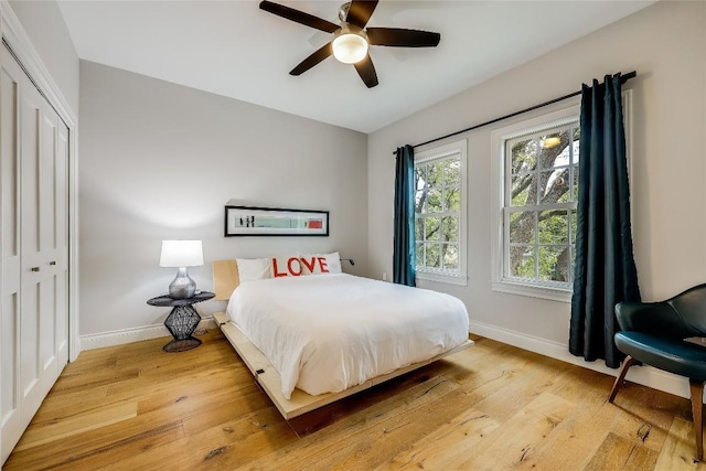 bedroom with ceiling fan, a closet, and light hardwood / wood-style floors