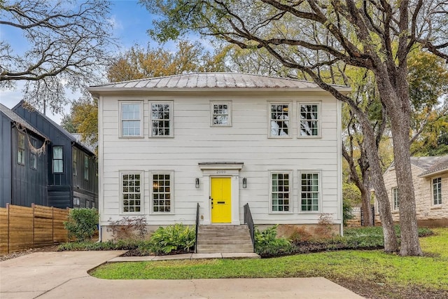 colonial inspired home with fence and metal roof