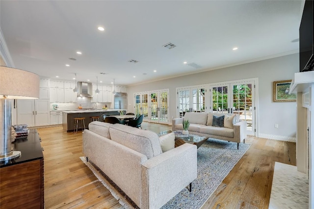 living room with french doors, light wood-type flooring, and crown molding