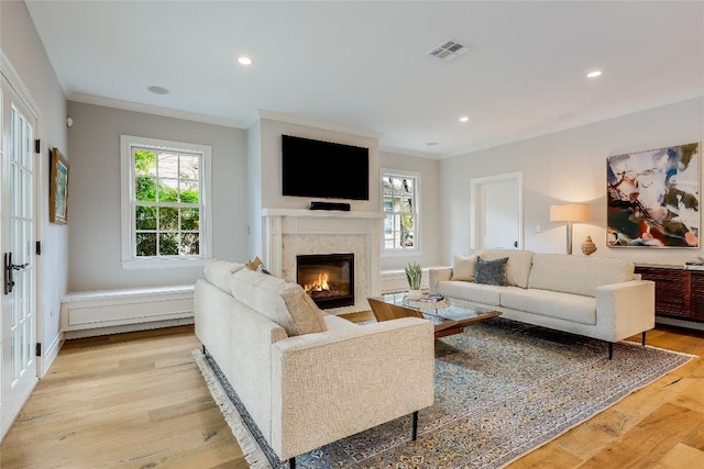 living room with a fireplace, visible vents, a wealth of natural light, and ornamental molding