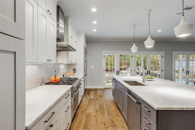 kitchen with white cabinets, french doors, decorative light fixtures, and wall chimney exhaust hood