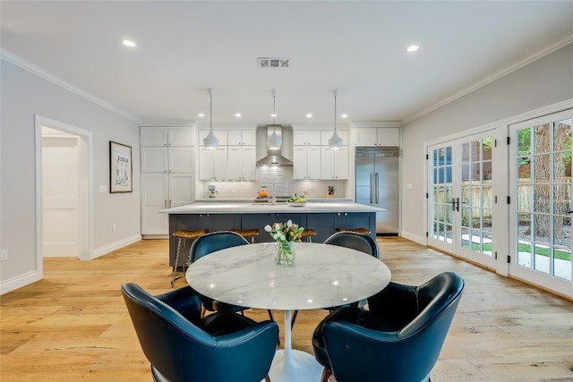 dining space with a wealth of natural light, french doors, crown molding, and light wood-type flooring