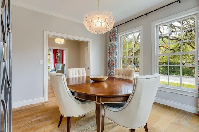 dining space featuring light wood-type flooring, an inviting chandelier, and crown molding