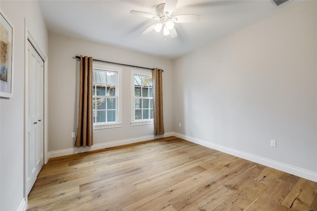 empty room with a ceiling fan, baseboards, and light wood-style floors