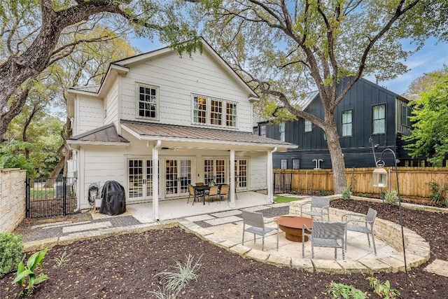 back of property featuring a fire pit, french doors, a patio, and a fenced backyard