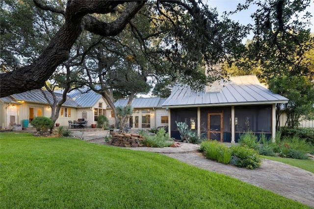 rear view of house featuring a lawn and a sunroom