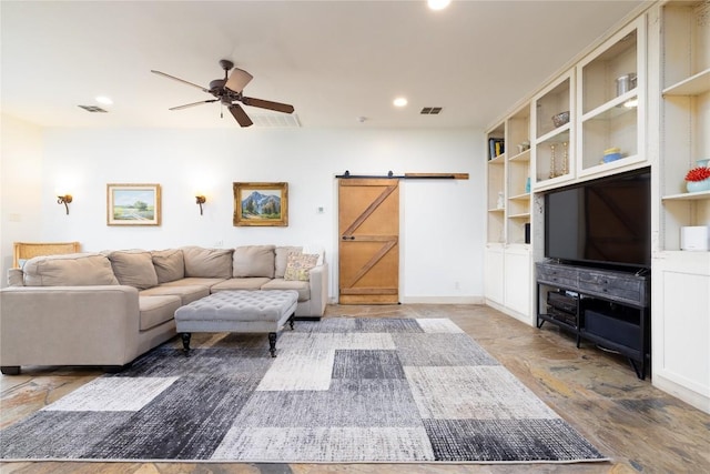 living room with a barn door and ceiling fan