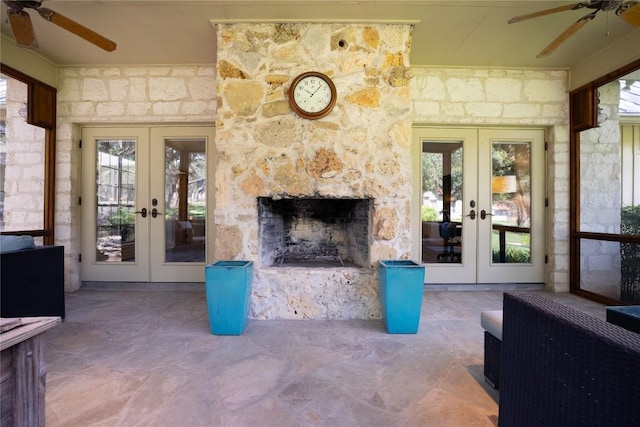 living room with french doors, a stone fireplace, and ceiling fan