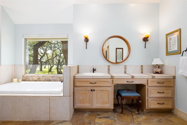 bathroom featuring a relaxing tiled tub and vanity