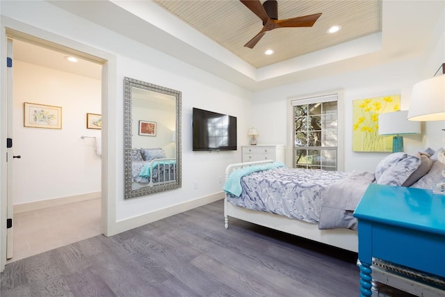 bedroom featuring ceiling fan, wood-type flooring, and a tray ceiling