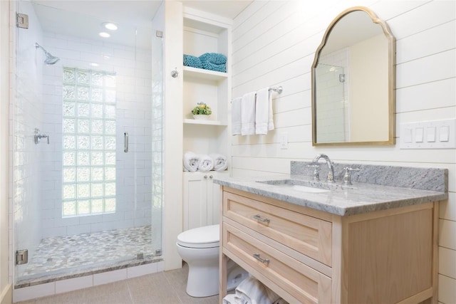 bathroom featuring vanity, wooden walls, tile patterned flooring, toilet, and walk in shower