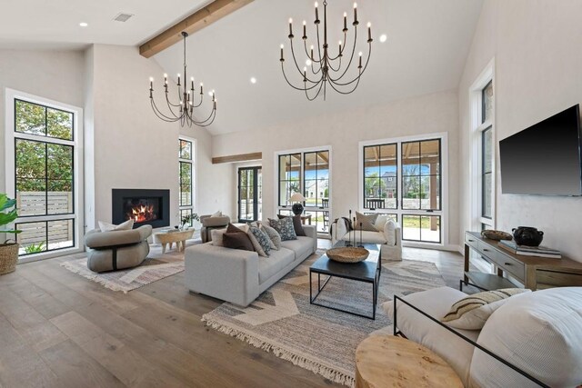 living room with beam ceiling, high vaulted ceiling, light hardwood / wood-style floors, and a notable chandelier