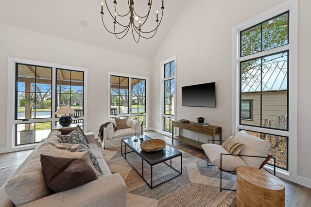 living room featuring light hardwood / wood-style floors, high vaulted ceiling, and a chandelier