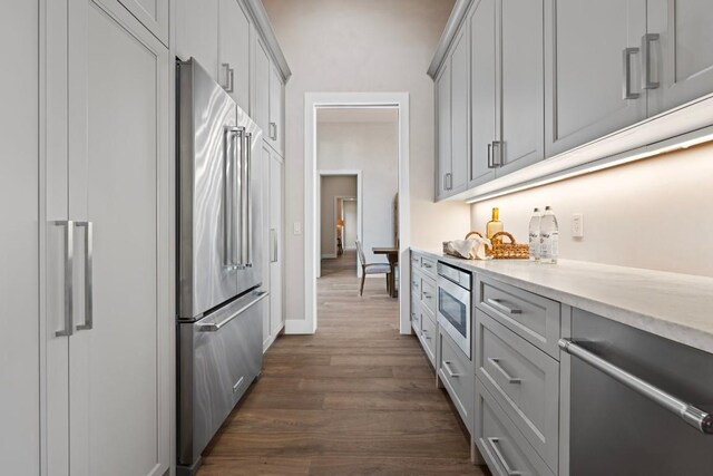 kitchen with appliances with stainless steel finishes, dark hardwood / wood-style floors, and gray cabinets