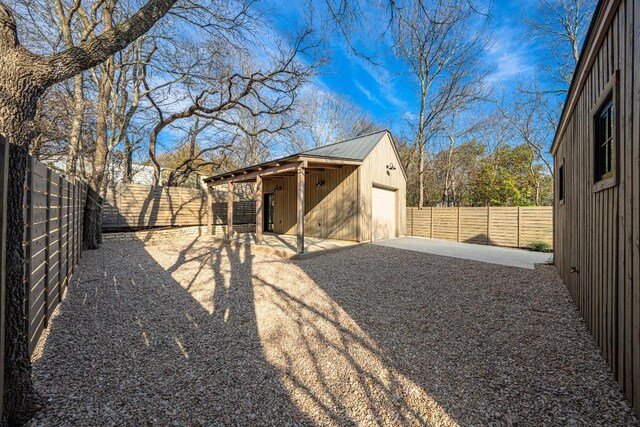 view of yard with a patio area, a garage, and an outbuilding