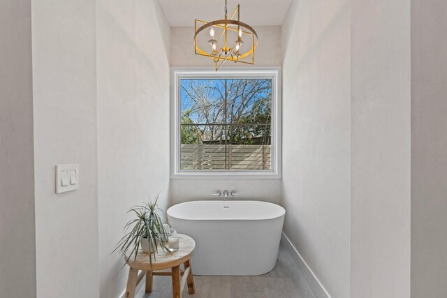 bathroom with a tub to relax in and a notable chandelier