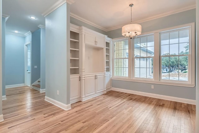 unfurnished dining area featuring light hardwood / wood-style floors, crown molding, and a notable chandelier