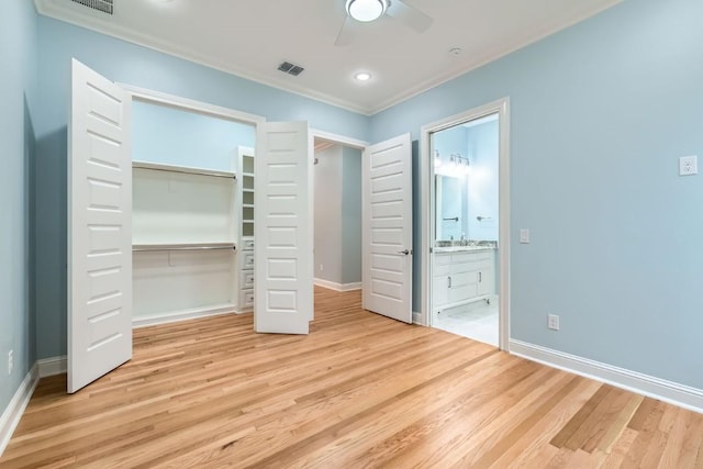 unfurnished bedroom with ensuite bath, ceiling fan, light hardwood / wood-style flooring, crown molding, and a closet