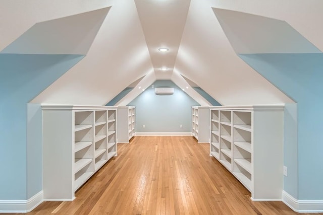 bonus room featuring light hardwood / wood-style floors, vaulted ceiling, and an AC wall unit