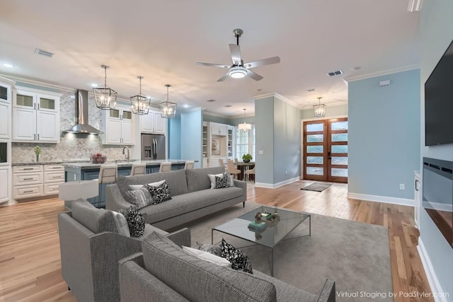 living room featuring crown molding, french doors, sink, and light wood-type flooring