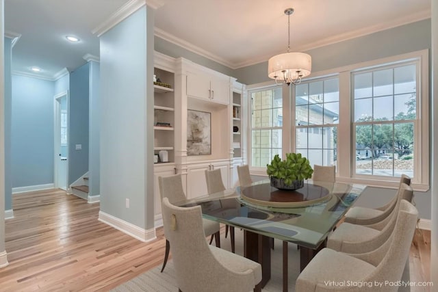 dining space with light hardwood / wood-style floors, ornamental molding, and a chandelier