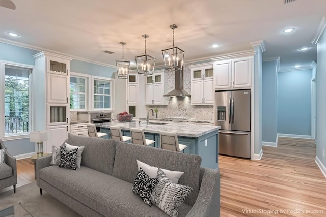 kitchen featuring backsplash, a center island with sink, decorative light fixtures, white cabinetry, and stainless steel appliances